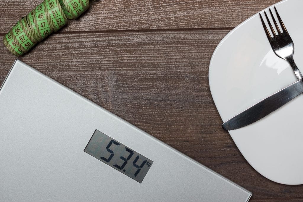 dieting concept with scales on wooden floor